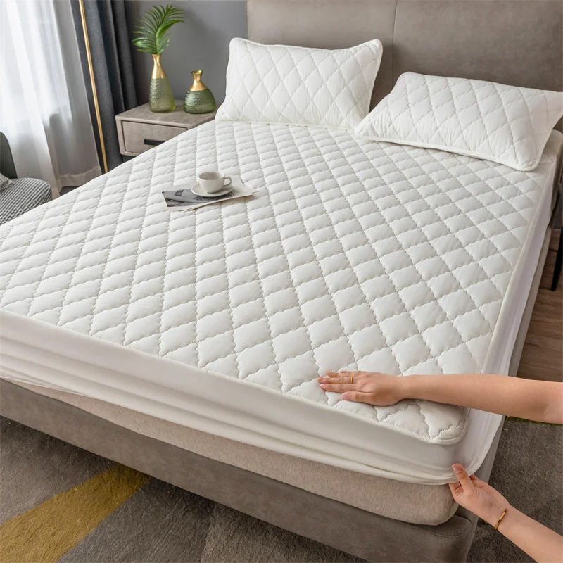 Protector de colchón antifluidos blanco puesto en una cama doble