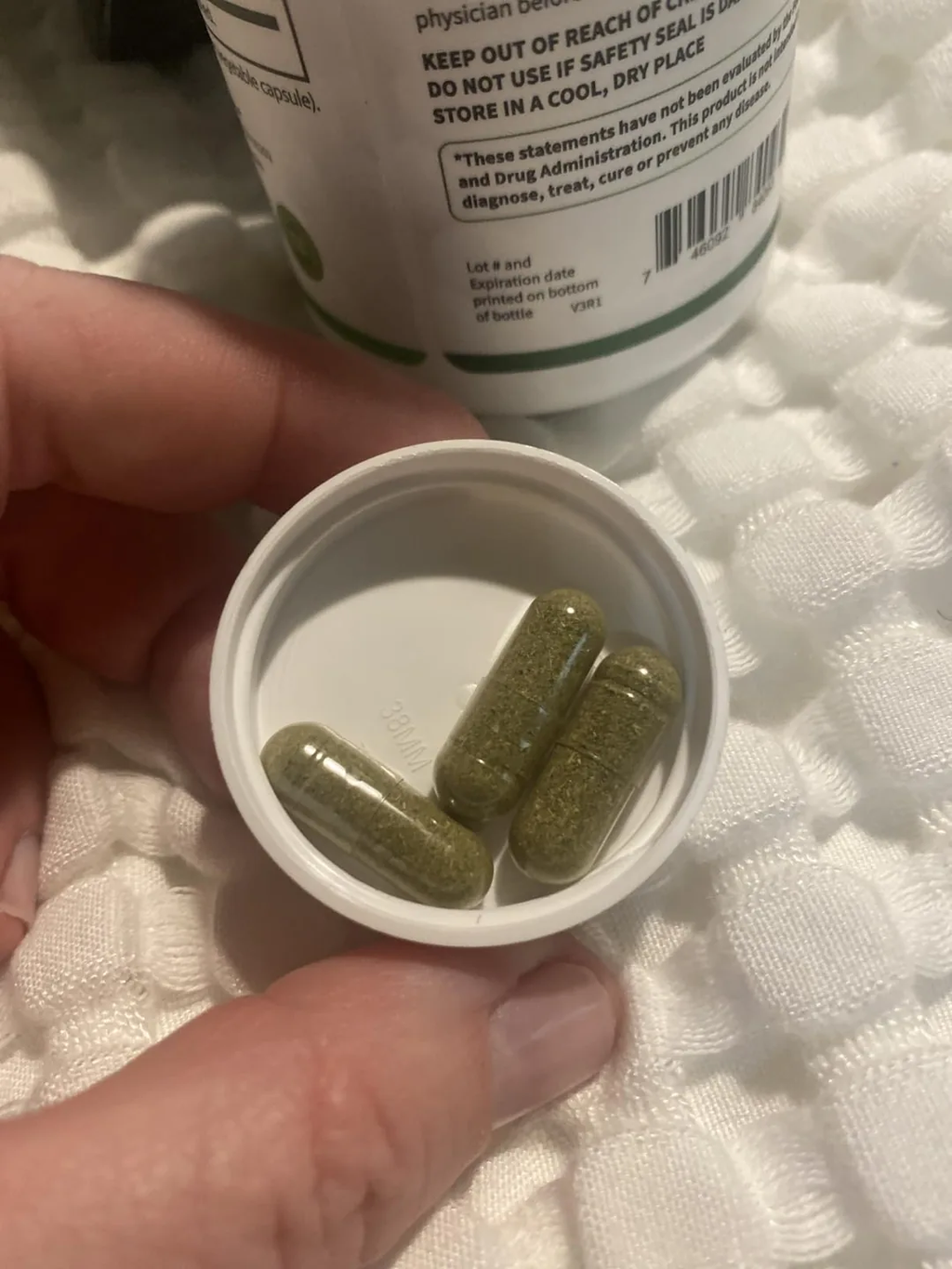Cápsulas verdes de moringa, tamaño real, en la tapa del frasco