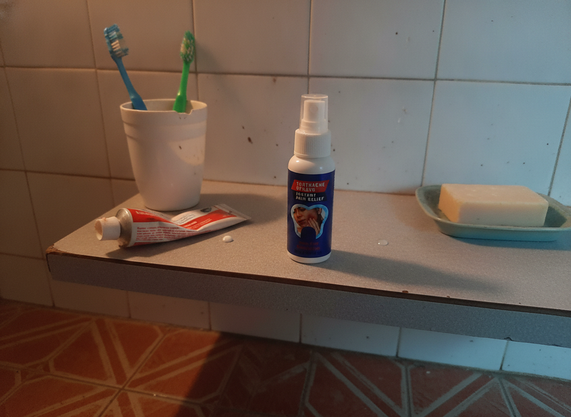 El frasco del spray en una repisa de ba&ntilde;o junto a los cepillos de dientes